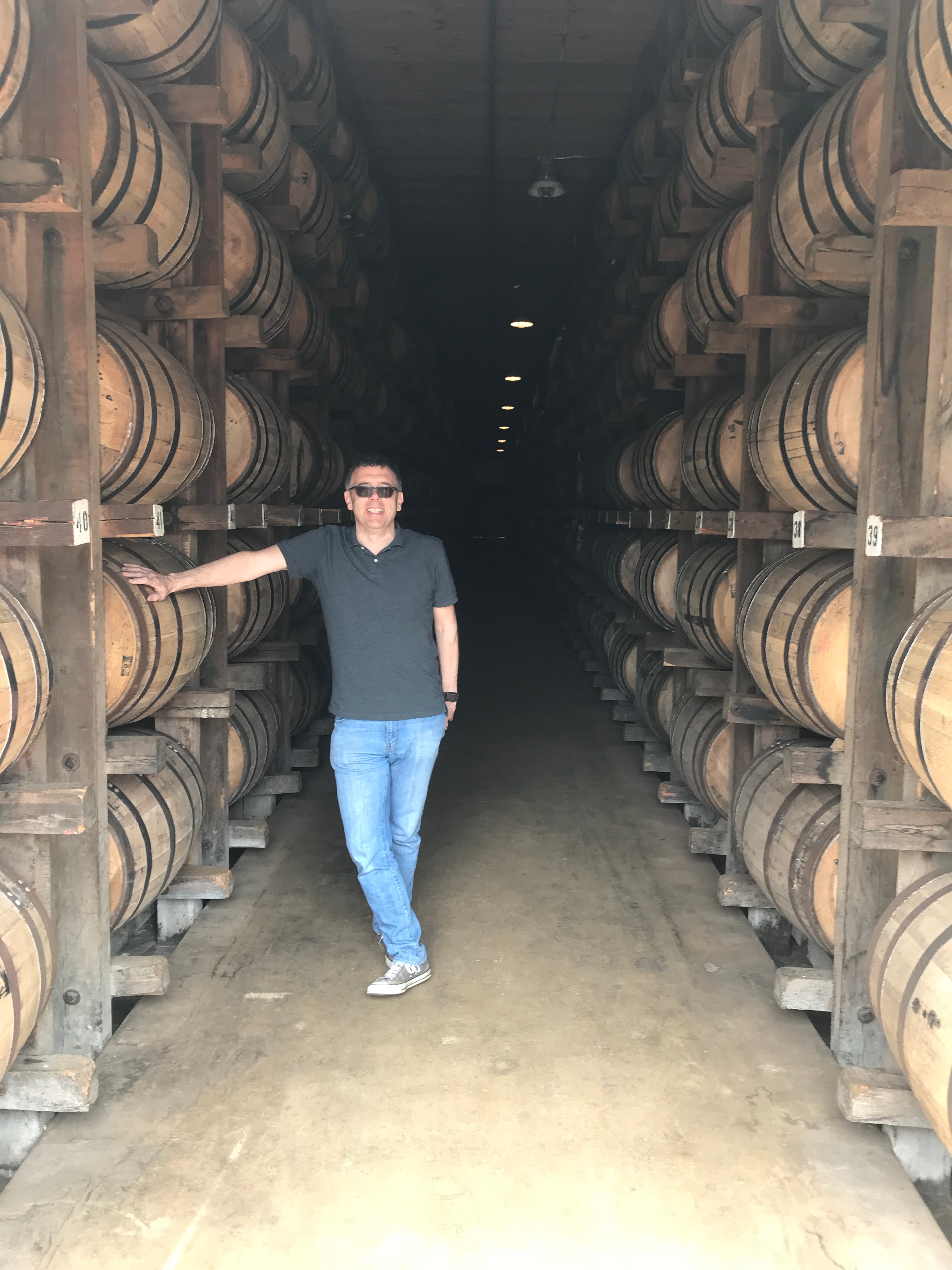 Gregor Cattanach standing between rows of whisky casks in a warehouse